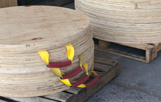 A stack of finished wooden outrigger pads with red and yellow handles.