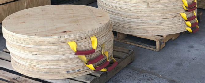 A stack of finished wooden outrigger pads with red and yellow handles.